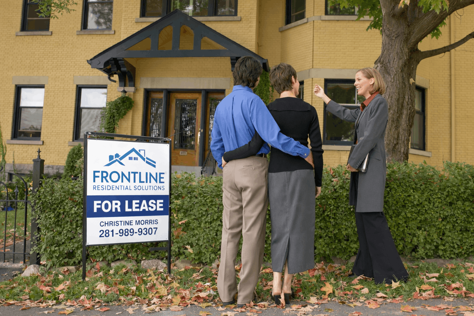 Couple viewing a rental property with a real estate agent near a Frontline Residential Solutions “For Lease” sign.